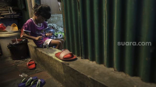 Seorang anak bermain di permukiman padat penduduk Kampung Muka RW 04, Ancol, Pademangan, Jakarta, Selasa (4/1/2022). [Suara.com/Angga Budhiyanto]