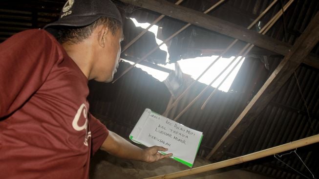 Petugas Badan Penanggulangan Bencana Daerah (BPBD) Kota Ternate melakukan pendataan rumah warga yang rusak akibat diterjang angin puting beliung di Kecamatan Pulau Moti, Kota Ternate, Maluku Utara, Selasa (4/1/2022).  ANTARA FOTO