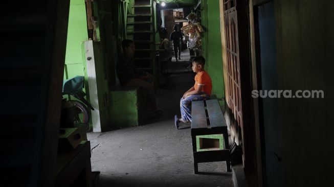 Seorang anak duduk di permukiman padat penduduk Kampung Muka RW 04, Ancol, Pademangan, Jakarta, Selasa (4/1/2022). [Suara.com/Angga Budhiyanto]