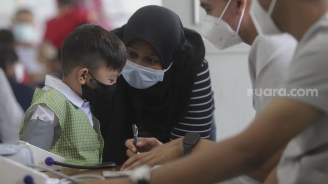 Tenaga kesehatan memeriksa kondisi kesehatan seorang anak sebelum mendapatkan vaksin COVID-19 di TK Kartika X-16, Mampang Prapatan, Jakarta, Selasa (4/1/2022). [Suara.com/Angga Budhiyanto]