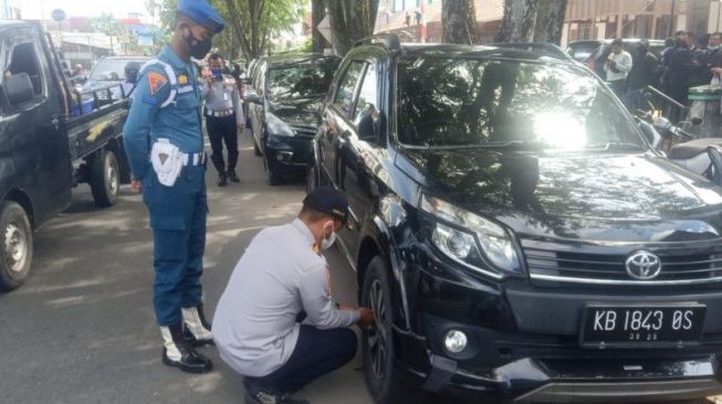 Personel Dinas Perhubungan Pontianak, Provinsi Kalimantan Barat, Senin (3/1/2022) mengempiskan ban mobil yang diparkir sembarangan di kota itu, Senin [ANTARA/HO-Dinas Perhubungan Pontianak]. 