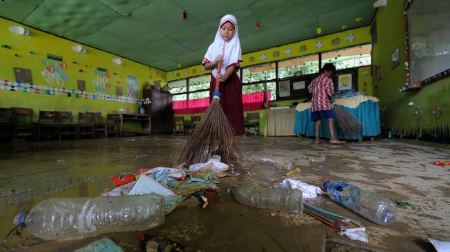 Pelajar SDN 145 Tanjung Menanti membersihkan ruang kelas yang terdampak banjir luapan Sungai Batang Tebo yang mulai surut di Bathin II Babeko, Bungo, Jambi, Rabu (5/1/2022).  ANTARA FOTO/Wahdi Septiawan