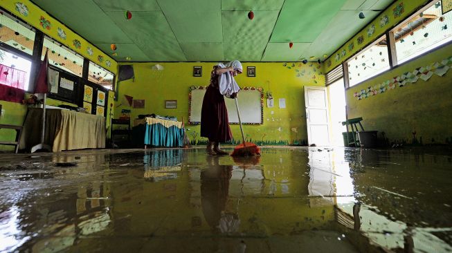 Pelajar SDN 145 Tanjung Menanti membersihkan ruang kelas yang terdampak banjir luapan Sungai Batang Tebo yang mulai surut di Bathin II Babeko, Bungo, Jambi, Rabu (5/1/2022).  ANTARA FOTO/Wahdi Septiawan