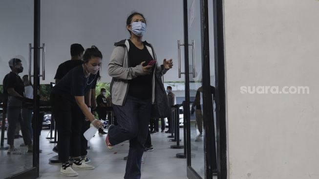 Petugas menyemprotkan cairan disinfektan kepada penonton dalam kegiatan simulasi kehadiran penonton saat pertandingan basket di Hall Basket Senayan, Jakarta, Jumat (7/1/2022). [Suara.com/Angga Budhiyanto]