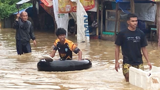 Sejumlah warga berjalan menerobos banjir di Pasar Youtefa Abepura, Jayapura,Papua, Jumat (7/1/2022). ANTARA FOTO/Fredy Fakdawer