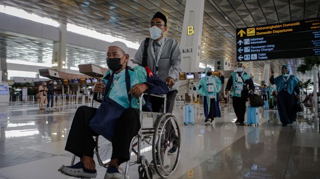 Sejumlah calon jamaah umrah berjalan sebelum menaiki pesawat di Terminal 3 Bandara Internasional Soekarno-Hatta, Tangerang, Banten, Sabtu (8/1/2022). ANTARA FOTO/Fauzan