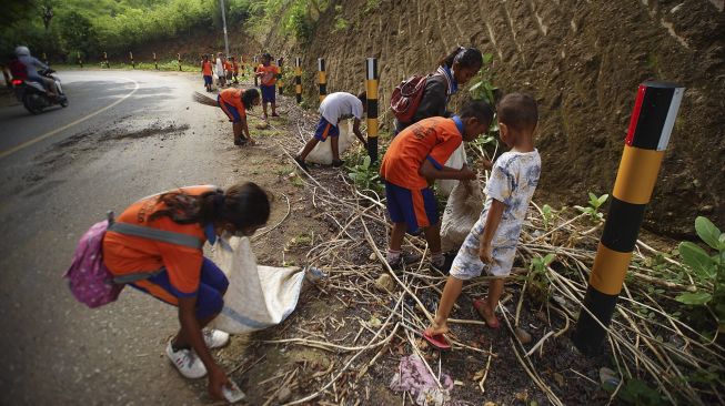 Sejumlah siswa SD Katolik Supilape mengumpulkan sampah plastik dan bekas popok yang dibuang di Jalan Trans Flores, Mbay, Kabupaten Nagekeo, NTT, Sabtu (8/1/2022). [ANTARA FOTO/Ignas Kunda]