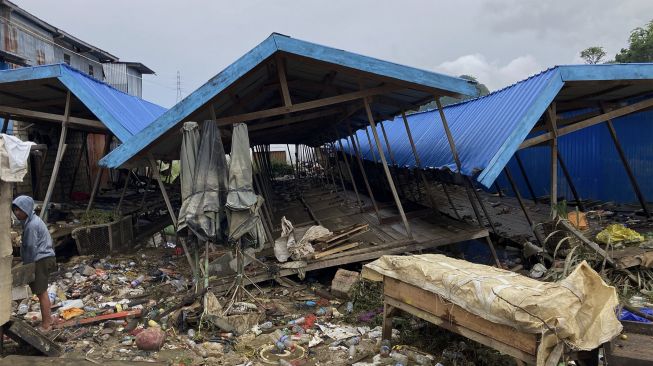 Warga berada di dekat bangunan yang rusak akibat banjir di Pasar Youtefa, Abepura, Jayapura, Papua, Minggu (9/1/2022). [ANTARA FOTO/Adharnazamudin]