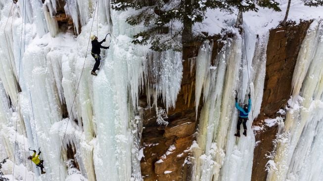 Foto udara pendaki memanjat dinding batu yang ditutupi pilar es selama Festival Panjat Tebing Es Sandstone, Minnesota, Amerika Serikat, pada (8/1/2022). [KEREM YUCEL / AFP]