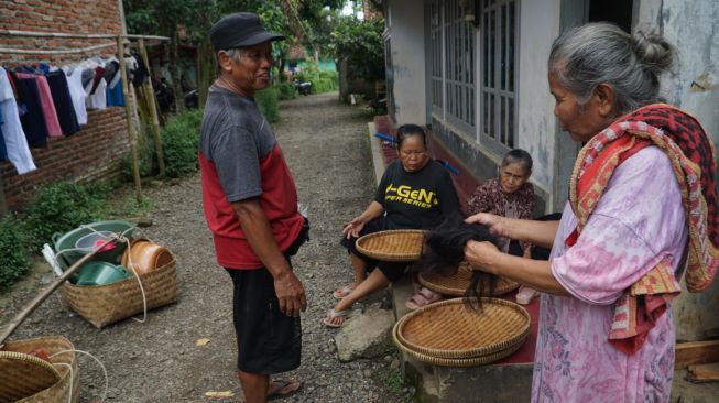 Mbah Supri menunjukkan rambut rontok pelanggannya yang digunakan untuk transaksi dagangan miliknya di Desa Gumelem Kulon, Kecamatan Susukan, Kabupaten Banjarnegara, Minggu (9/1/2022). [Suara.com/Anang Firmansyah]