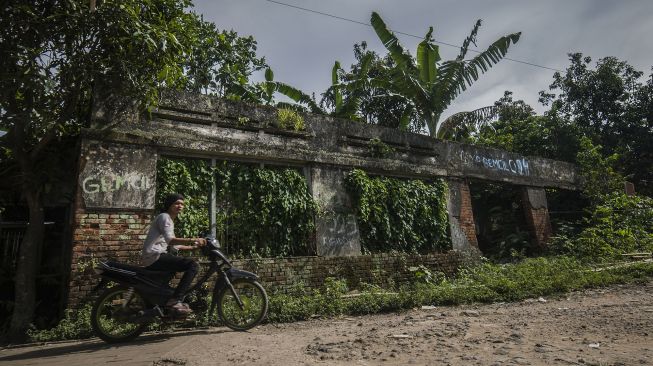 Warga melintas di depan stasiun Pandeglang yang terbengkalai di Pandeglang, Banten, Minggu (9/1/2022). [ANTARA FOTO/Muhammad Bagus Khoirunas]