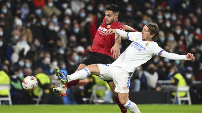 Bek Valencia Hugo Guillamon (kiri) bersaing dengan gelandang Real Madrid Luka Modric selama pertandingan sepak bola liga Spanyol antara Real Madrid CF dan Valencia CF di Stadion Santiago Bernabeu, Madrid, pada (8/1/2022). [GABRIEL BOUYS / AFP]