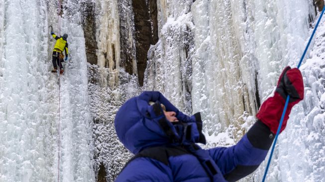 Pendaki memanjat dinding batu yang ditutupi pilar es selama Festival Panjat Tebing Es Sandstone, Minnesota, Amerika Serikat, pada (7/1/2022). [KEREM YUCEL / AFP]