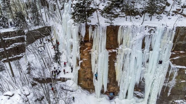 Foto udara pendaki memanjat dinding batu yang ditutupi pilar es selama Festival Panjat Tebing Es Sandstone, Minnesota, Amerika Serikat, pada (8/1/2022). [KEREM YUCEL / AFP]