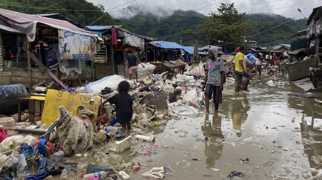 Sejumlah warga melintasi tumpukan sampah akibat banjir di Pasar Youtefa, Abepura, Jayapura, Papua, Minggu (9/1/2022). [ANTARA FOTO/Adharnazamudin]