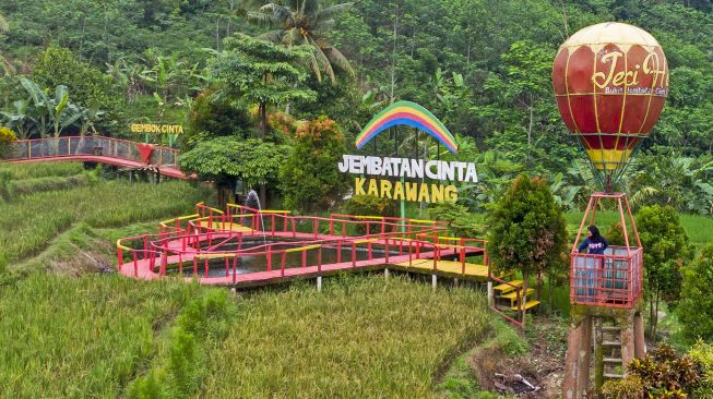 Pengunjung menikmati suasana wisata Jembatan Cinta di Desa Mekarbuana, Tegalwaru, Karawang, Jawa Barat, Minggu (9/1/2022).  ANTARA FOTO/M Ibnu Chazar