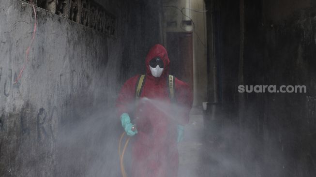 Petugas pemadam kebakaran menyemprotkan cairan disinfektan di Kelurahan Krukut, Kecamatan Taman Sari, Jakarta, Senin (10/1/2021). [Suara.com/Angga Budhiyanto]