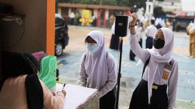 Un certain nombre d'élèves utilisent un dispositif de contrôle de la température avant d'entrer dans une école de la ville de Bandung, dans l'ouest de Java. [ANTARA/HO-Diskominfo Kota Bandung]