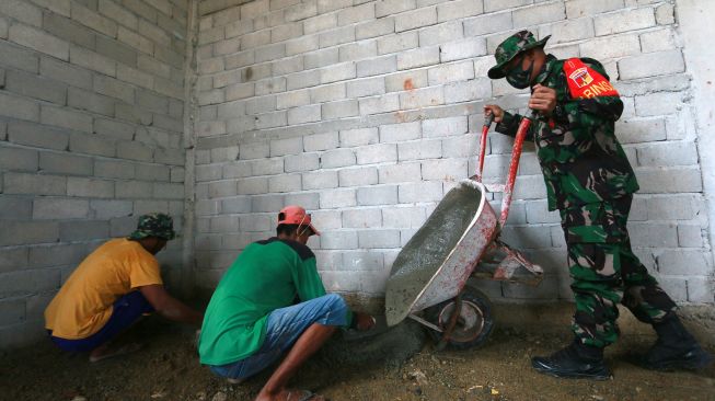 Bintara Pembina Desa (Babinsa) Sersan Dua (Serda) Ishak Nur (kanan) membawa material untuk pembangunan Masjid Al Muhadjirin di Desa Pilolalenga, Kabupaten Gorontalo, Gorontalo, Senin (10/1/2022).  ANTARA FOTO/Adiwinata Solihin