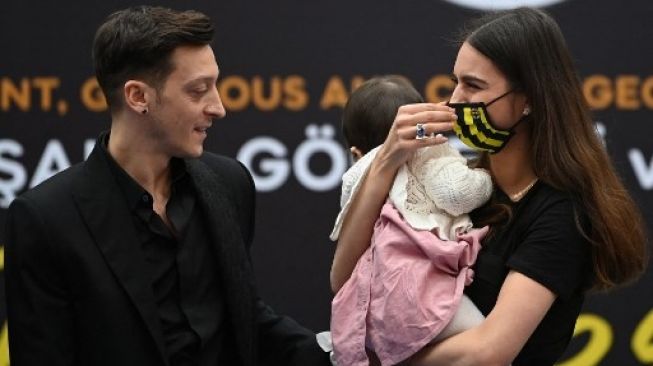 Mesut Ozil bersama istrinya, Amine Gulse, dan juga putrinya yang bernama Eda berpose usai acara penandatanganan kontrak baru bersama Fenerbahce pada 27 Januari 2021. [AFP]