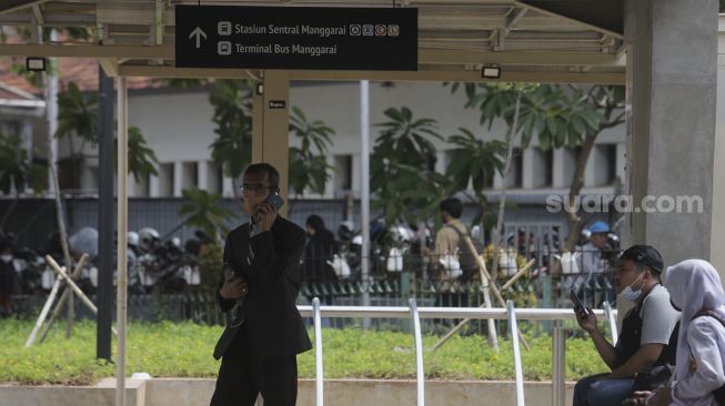 Warga menunggu kedatangan bus di kawasan integrasi terpadu Stasiun Manggarai, Kecamatan Tebet, Jakarta Selatan, Senin (10/1/2021). [Suara.com/Angga Budhiyanto]