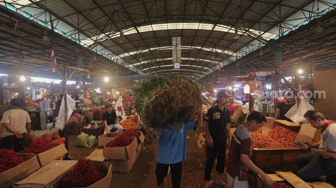 Buruh angkut membawa sayuran di Pasar Induk Kramat Jati, Jakarta, Rabu (12/1/2022). [Suara.com/Angga Budhiyanto]