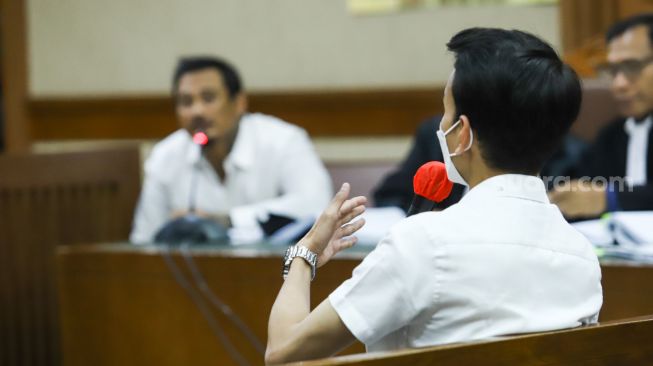 Adam Deni yang hadir sebagai saksi menjawab pertanyaan yang diajukan terdakwa Musisi I Gede Ari Astina atau Jerinx SID saat sidang kasus pengancaman di Pengadilan Negeri Jakarta Pusat, Rabu (12/1/2022). [Suara.com/Alfian Winanto]