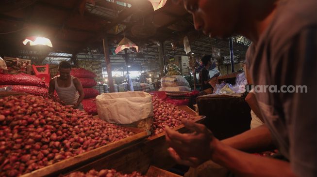 Pedagang memilah bawang merah di Pasar Induk Kramat Jati, Jakarta, Rabu (12/1/2022). [Suara.com/Angga Budhiyanto]