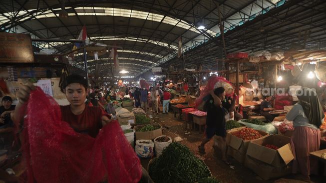 Buruh angkut membawa sayuran di Pasar Induk Kramat Jati, Jakarta, Rabu (12/1/2022). [Suara.com/Angga Budhiyanto]