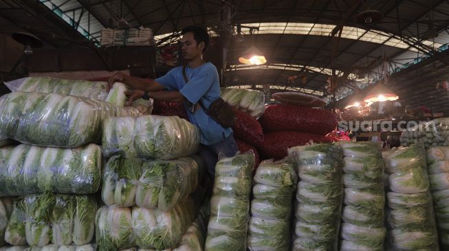 Pedagang menata sayuran di Pasar Induk Kramat Jati, Jakarta, Rabu (12/1/2022). [Suara.com/Angga Budhiyanto]