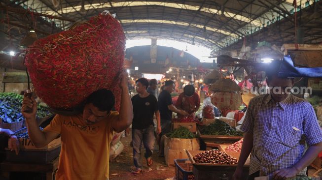 Buruh angkut membawa cabai di Pasar Induk Kramat Jati, Jakarta, Rabu (12/1/2022). [Suara.com/Angga Budhiyanto]