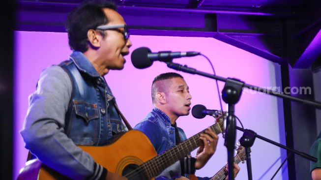Aksi Band The Rain ketika tampil bernyanyi saat berkunjung ke kantor redaksi Suara.com di Kuningan, Jakarta Selatan, Kamis (13/1/2022). [Suara.com/Alfian Winanto]
