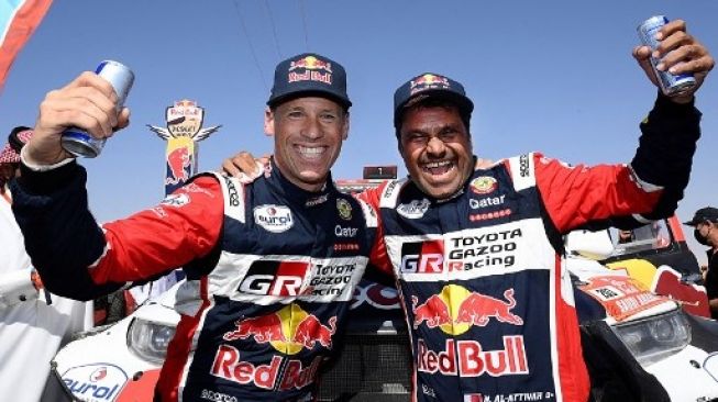 Pebalap Toyota Nasser al-Attiyah dari Qatar (kanan) dan co-driver Mathieu Baumel dari Prancis merayakan kemenangan mereka setelah memenangkan Reli Dakar 2022, pada akhir etape terakhir antara Bisha dan Jeddah di Arab Saudi, pada 14 Januari 2022FRANCKFIFE/AFP