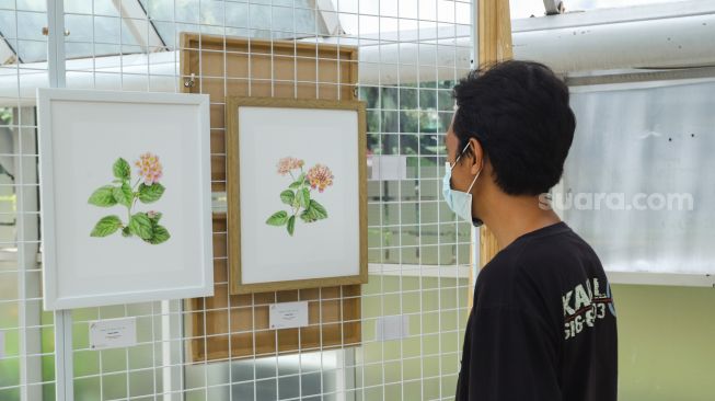 Pengunjung melihat sejumlah karya seni dalam gelaran Jakarta Biennale yang berlangsung di Rumah Kaca Taman Menteng, Jakarta Pusat, Sabtu (15/1/2022). [Suara.com/Alfian Winanto]
