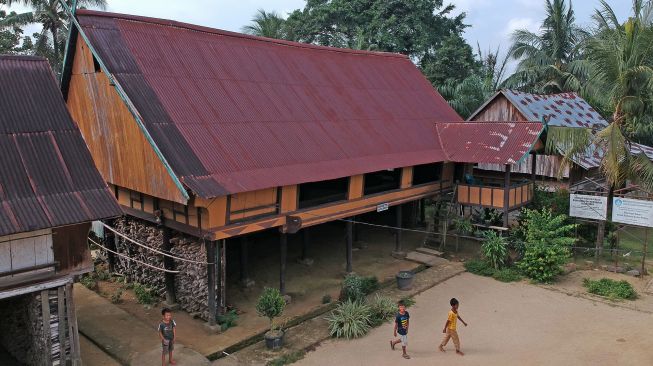 Tiga bocah bermain di halaman depan cagar budaya Rumah Tradisional Rantau Panjang atau Rumah Tuo di Kampung Baru, Tabir, Merangin, Jambi, Sabtu (15/1/2022).  ANTARA FOTO/Wahdi Septiawan