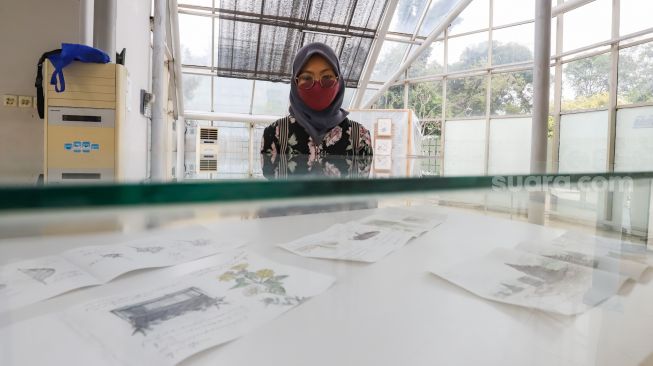 Pengunjung melihat sejumlah karya seni dalam gelaran Jakarta Biennale yang berlangsung di Rumah Kaca Taman Menteng, Jakarta Pusat, Sabtu (15/1/2022). [Suara.com/Alfian Winanto]
