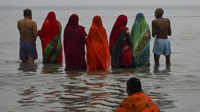 Peziarah Hindu melakukan ritual doa setelah berenang suci di pertemuan Gangga dan Teluk Benggala selama Gangasagar Mela pada kesempatan Makar Sankranti di Pulau Sagar, India, pada (14/1/2022). [DIBYANGSHU SARKAR / AFP]