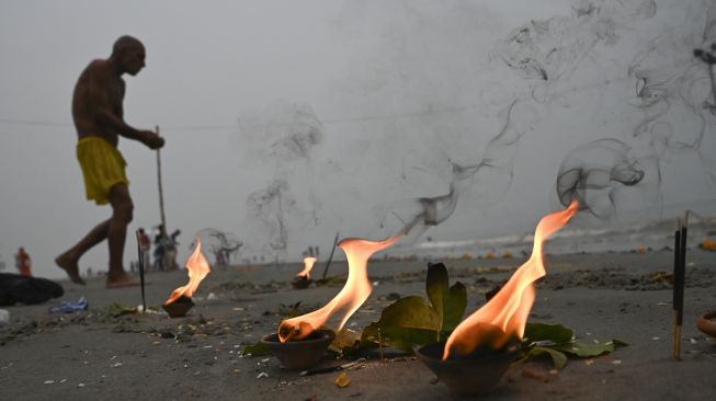 Seorang peziarah Hindu berjalan untuk berenang suci di pertemuan Gangga dan Teluk Benggala selama Gangasagar Mela pada kesempatan Makar Sankranti di Pulau Sagar, India, pada (14/1/2022). [DIBYANGSHU SARKAR / AFP]