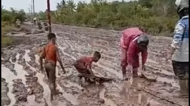Jalanan rusak dan penuh lumpur membuat anak-anak SD membantu para pemotor untuk memberikan akses (Facebook)