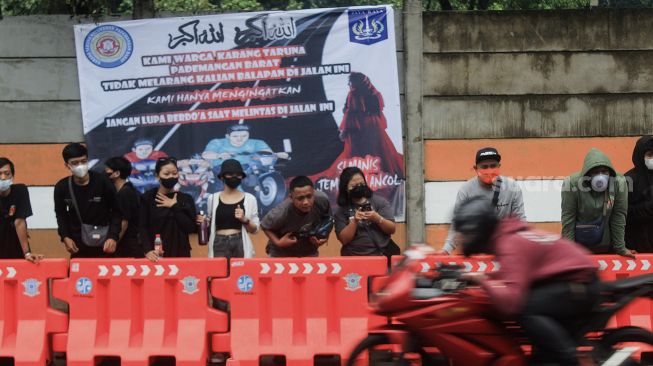 Penonton menyaksikan ajang Street Race Polda Metro Jaya di Ancol, Jakarta, Minggu (16/1/2022). [Suara.com/Septian]