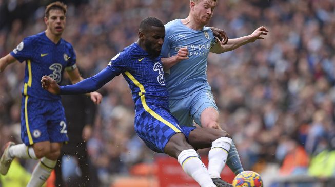 Bek Chelsea Antonio Rudiger (kiri) menjegal gelandang Manchester City Kevin De Bruyne selama pertandingan sepak bola Liga Premier Inggris antara Manchester City dan Chelsea di Stadion Etihad, Manchester, Inggris, Sabtu (15/1/2022). [OLI SCARFF / AFP]