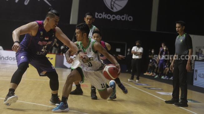 Pebasket Pacific Caesar Surabaya (kanan) berusaha melewati hadangan pebasket RANS PIK Basketball Club Valentino Wuwungan saat bertanding pada Indonesian Basketball League (IBL) 2022, di Hall Basket Gelora Bung Karno, Senayan, Jakarta, Senin (17/1/2022). [Suara.com/Angga Budhiyanto]