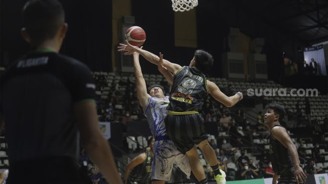 Pebasket West Bandits Combiphar Solo Rio Disi (kedua kanan) memblok lemparan bola dari pebasket Prawira Bandung Abraham Damar Grahita pada pertandingan Seri 1 Jakarta Indonesian Basketball League (IBL) 2022 di Hall Basket Senayan, GBK, Jakarta, Senin (17/1/2022). [Suara.com/Angga Budhiyanto]