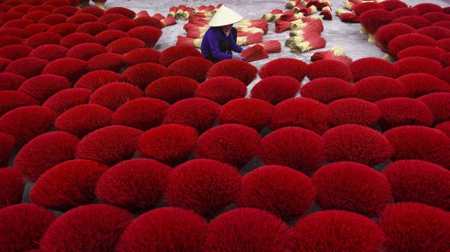 Seorang pekerja mengumpulkan dupa kering di Desa Quang Phu Cau, Hanoi, Vietnam, pada (12/1/2022). [NHAC NGUYEN / AFP]