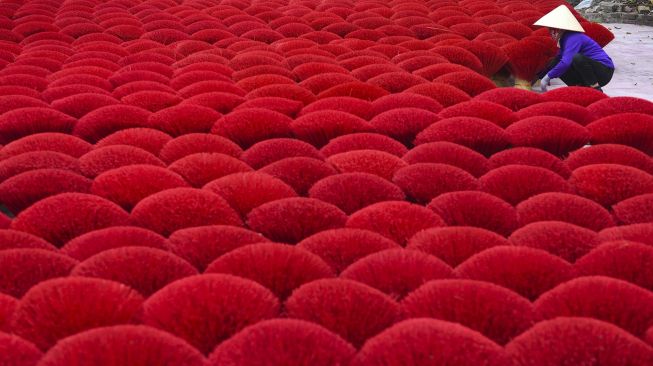 Seorang pekerja mengumpulkan dupa kering di Desa Quang Phu Cau, Hanoi, Vietnam, pada (12/1/2022). [NHAC NGUYEN / AFP]