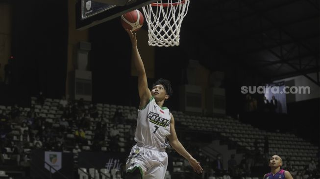 Pebasket Pacific Caesar Surabaya Gregorio Claudie Wibowo melakukan layup melewati pemain RANS PIK Basketball Club saat bertanding pada Indonesian Basketball League (IBL) 2022, di Hall Basket Gelora Bung Karno, Senayan, Jakarta, Senin (17/1/2022). [Suara.com/Angga Budhiyanto]