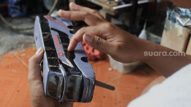 Andy Kunaryo (34) menyelesaikan pembuatan miniatur bus di Workshop Belang Bentong, Limo, Depok, Jawa Barat, Senin (17/1/2022). [Suara.com/Septian]