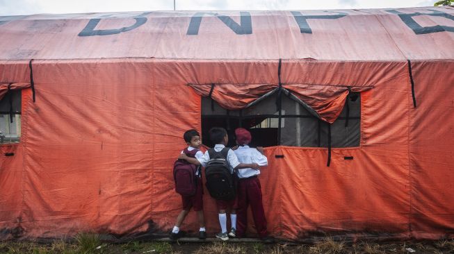 Siswa melihat proses kegiatan belajar mengajar di dalam tenda darurat di MTs Mathlahul Anwar Sumur, Pandeglang, Banten, Senin (17/1/2022). [ANTARA FOTO/Muhammad Bagus Khoirunas]