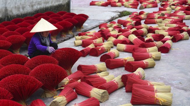 Seorang pekerja mengumpulkan dupa kering di Desa Quang Phu Cau, Hanoi, Vietnam, pada (12/1/2022). [NHAC NGUYEN / AFP]