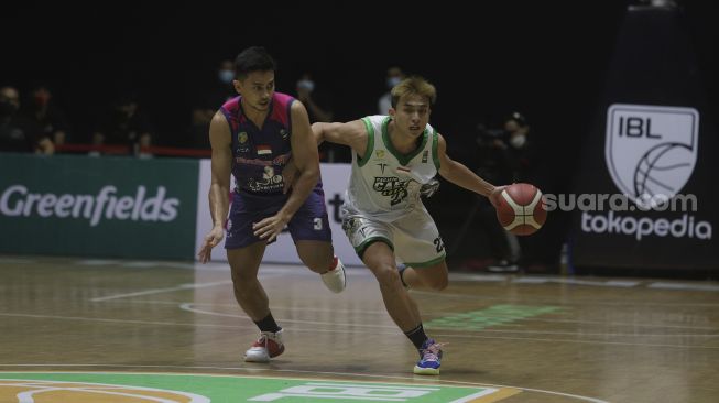 Pebasket Pacific Caesar Surabaya Calvin Chrissler (kanan) berusaha melewati hadangan pebasket Pebasket RANS PIK Basketball Club Nuke Tri Saputra saat bertanding pada Indonesian Basketball League (IBL) 2022, di Hall Basket Gelora Bung Karno, Senayan, Jakarta, Senin (17/1/2022). [Suara.com/Angga Budhiyanto]